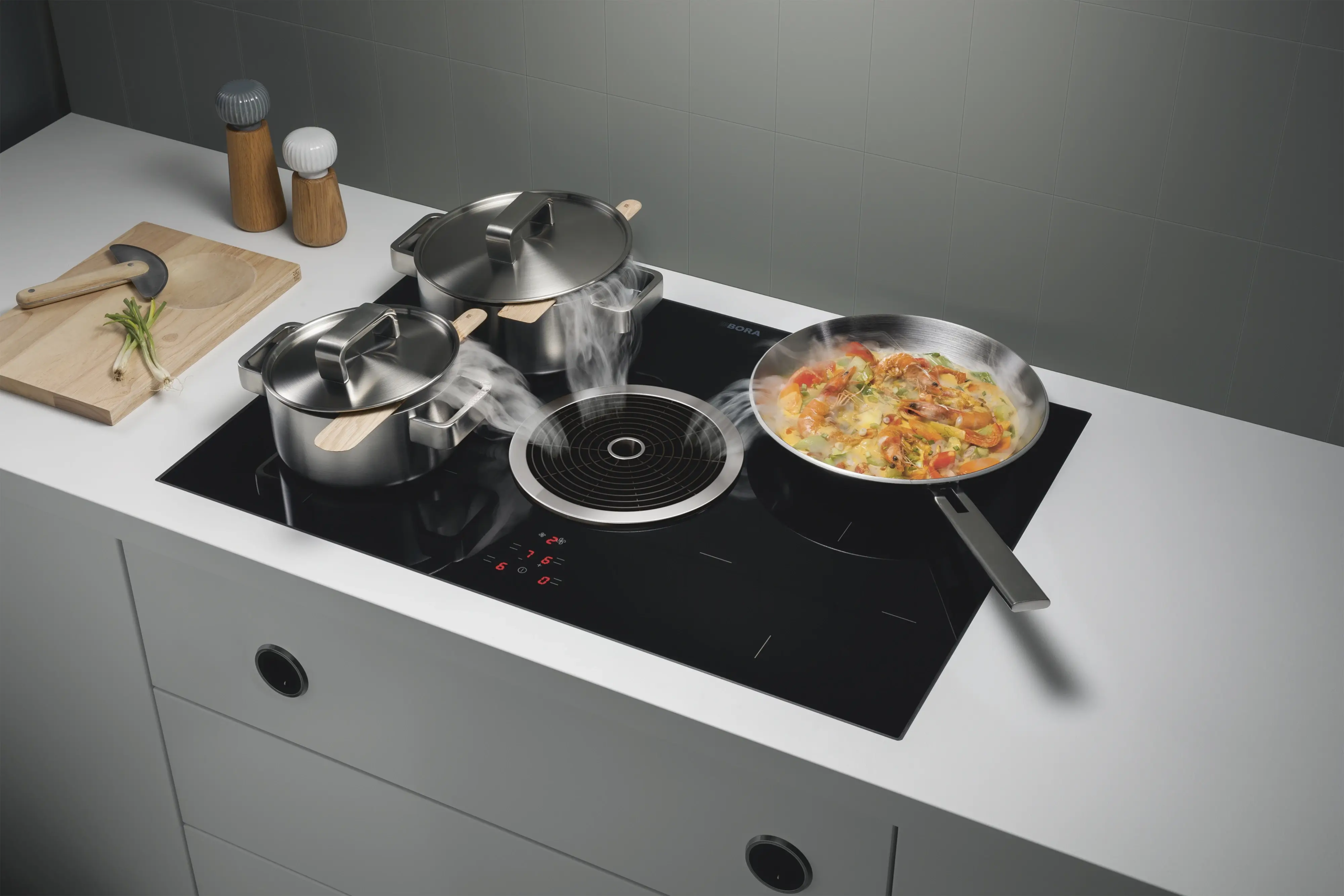 2 BORA Basic ploča za kuvanje sa aspiratorom, ugrađena u belu radnu ploču, prikazana tokom kuvanja