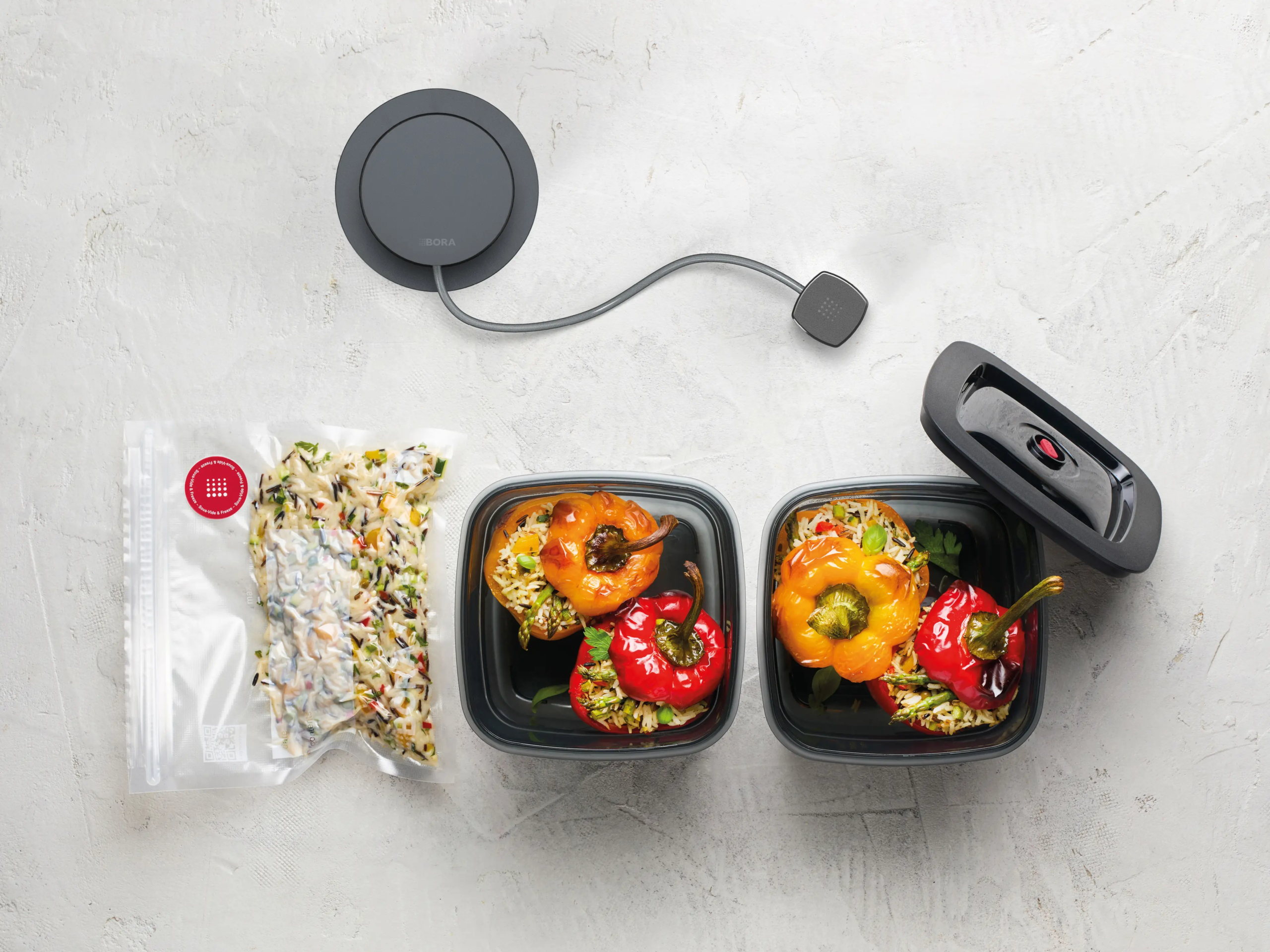 2 BORA QVac sistem sa vakuumskim posudama i kesom sa hranom, prikaz funkcionalnosti na svetloj podlozi.