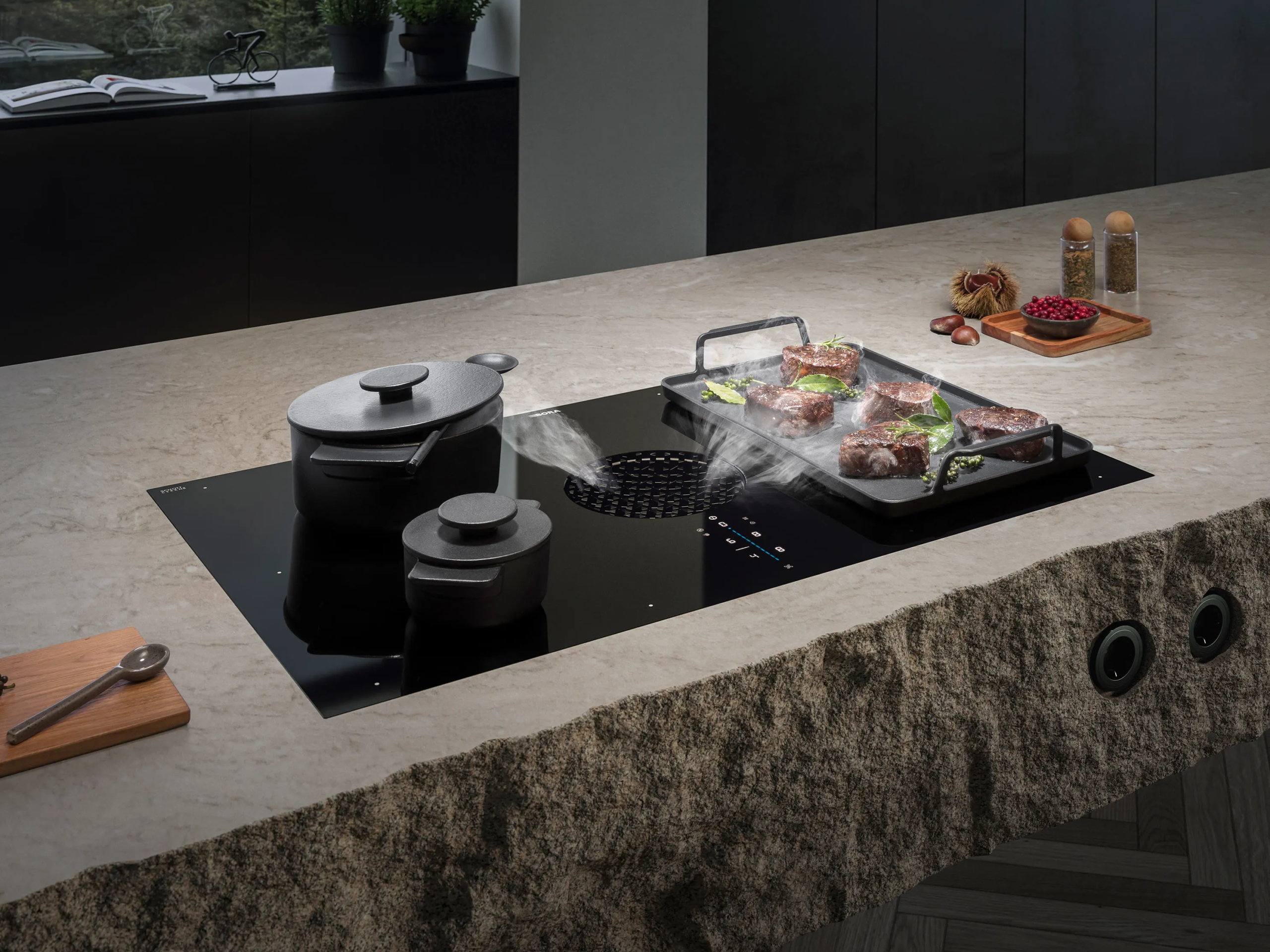 5 BORA X Pure sistem u modernoj kuhinji sa kamenom radnom površinom, posudama i grilom na kojem se priprema meso — para se nežno uvlači kroz centralni otvor.