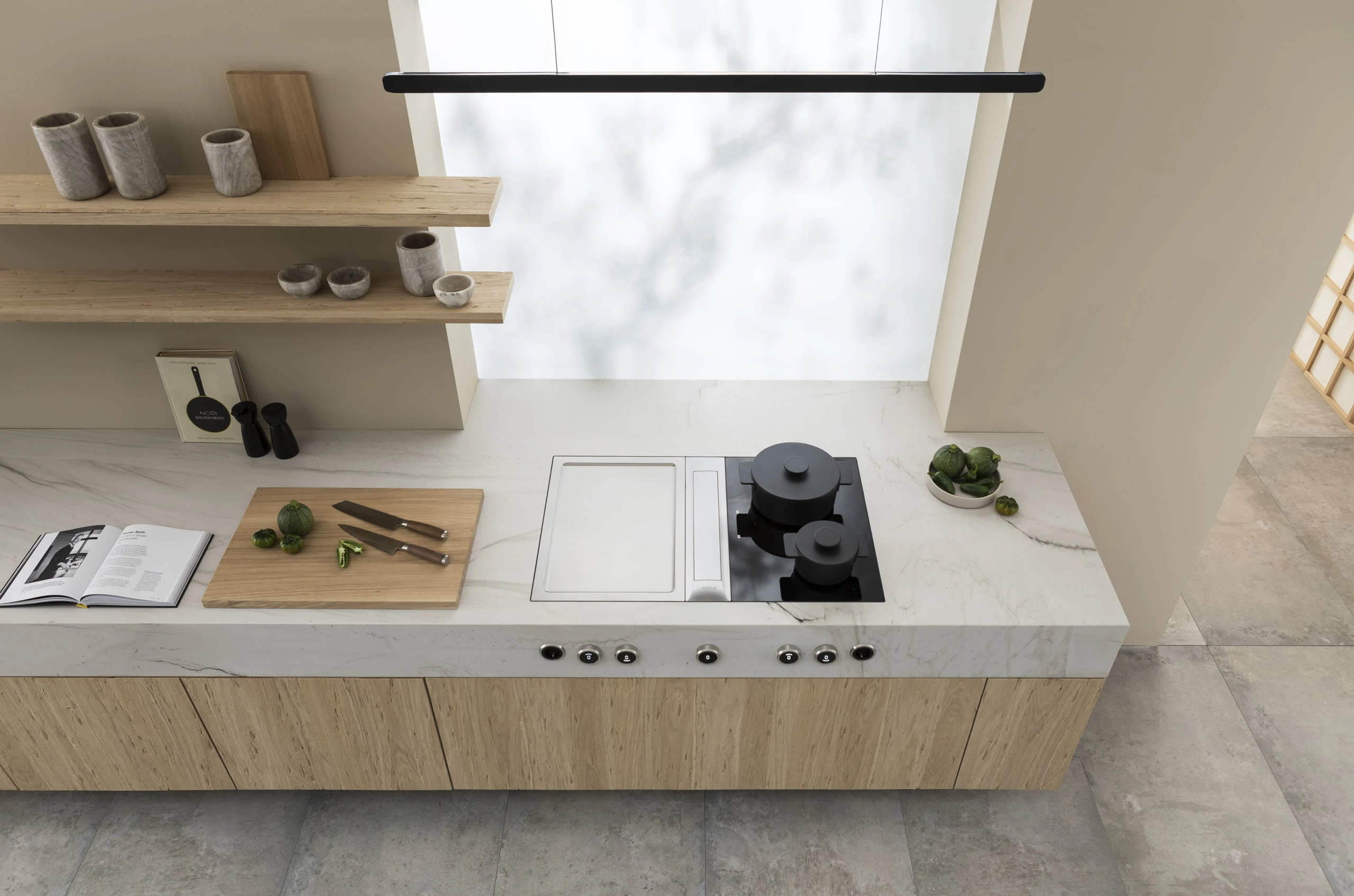 6 (1) Kuhinja u svetlim tonovima sa BORA Professional 3.0 aspiratorom i pločama – priprema jela uz prirodno osvetljenje i minimalističan enterijer.