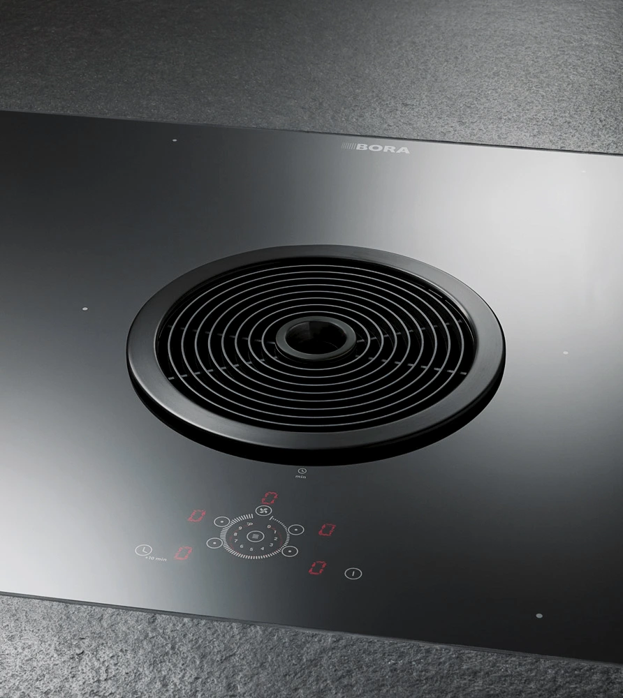 7 BORA Basic – detalj centralnog otvora aspiratora i touch kontrola na staklokeramičkoj površini, elegantni crni dizajn.
