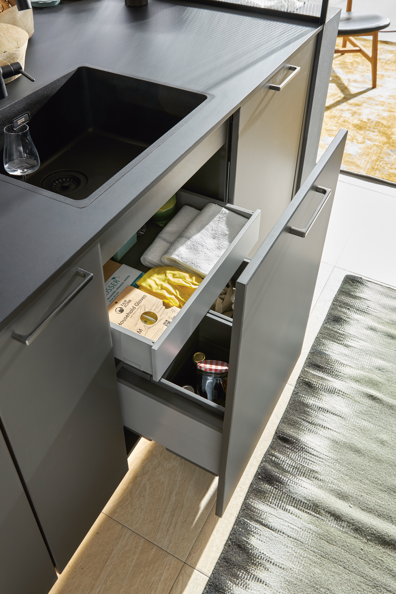 SGM-A112_FMA-L187U_Auszug-5_2023 Detalj Schüller Smartglas matt kuhinje u "Onyx black" finišu od polimernog stakla, sa otvorenom fiokom ispod sudopere.