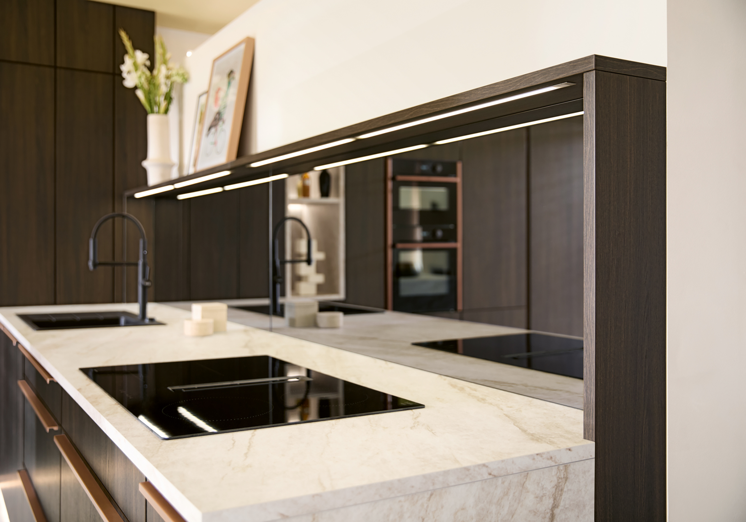 VAR-K833_Spiegelnische_2026 Dizajnerski vrhunac Schüller Varese kuhinje: niša od ogledalo stakla koja reflektuje svetlost, ploču za kuvanje i mermernu radnu ploču.