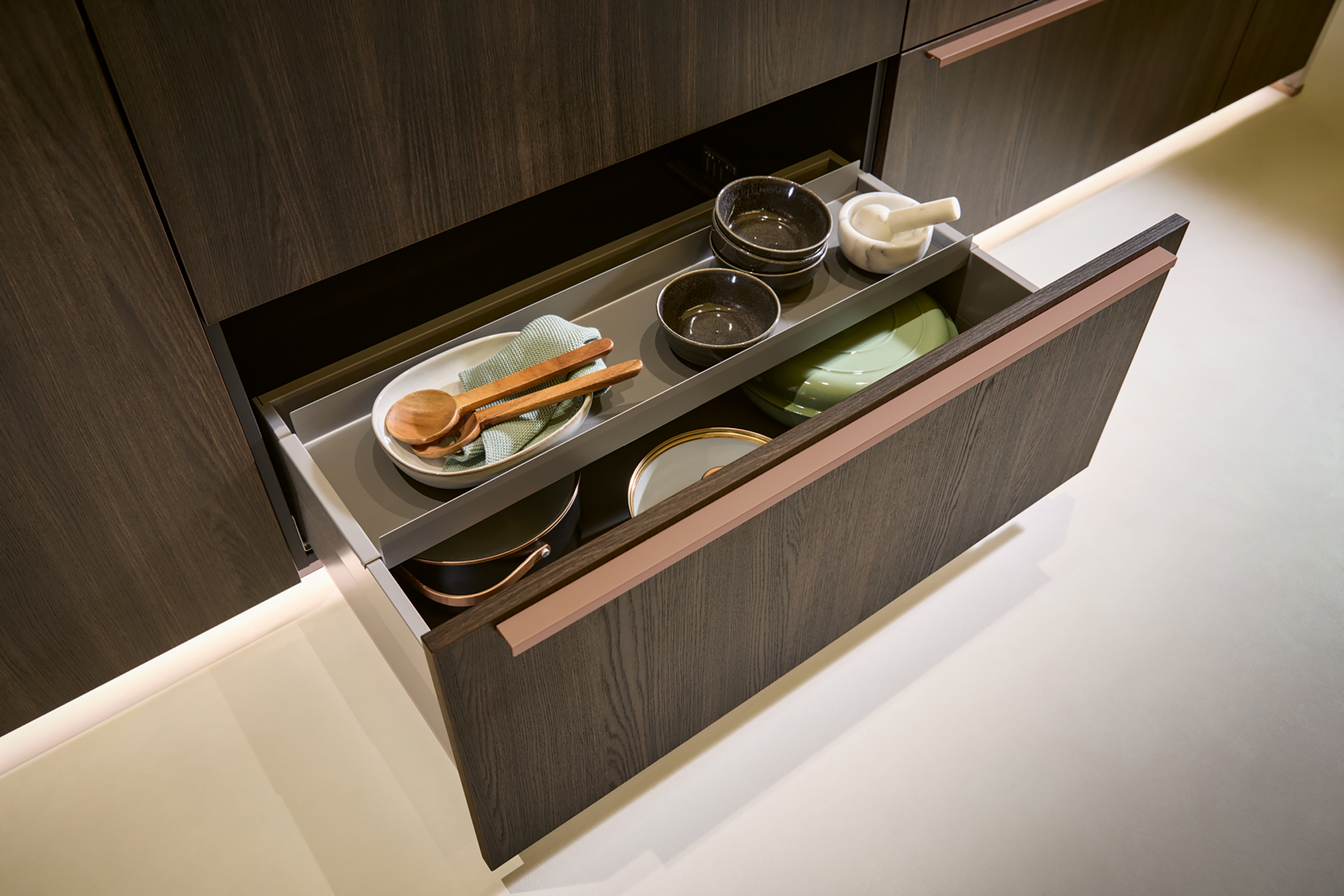 VAR-K833_Zargenauflage_2026 Detalj fioke Schüller Varese: front od taktilnog "Sinhropor" hrasta Sijena sa elegantnom linearnom bronzanom ručkom.