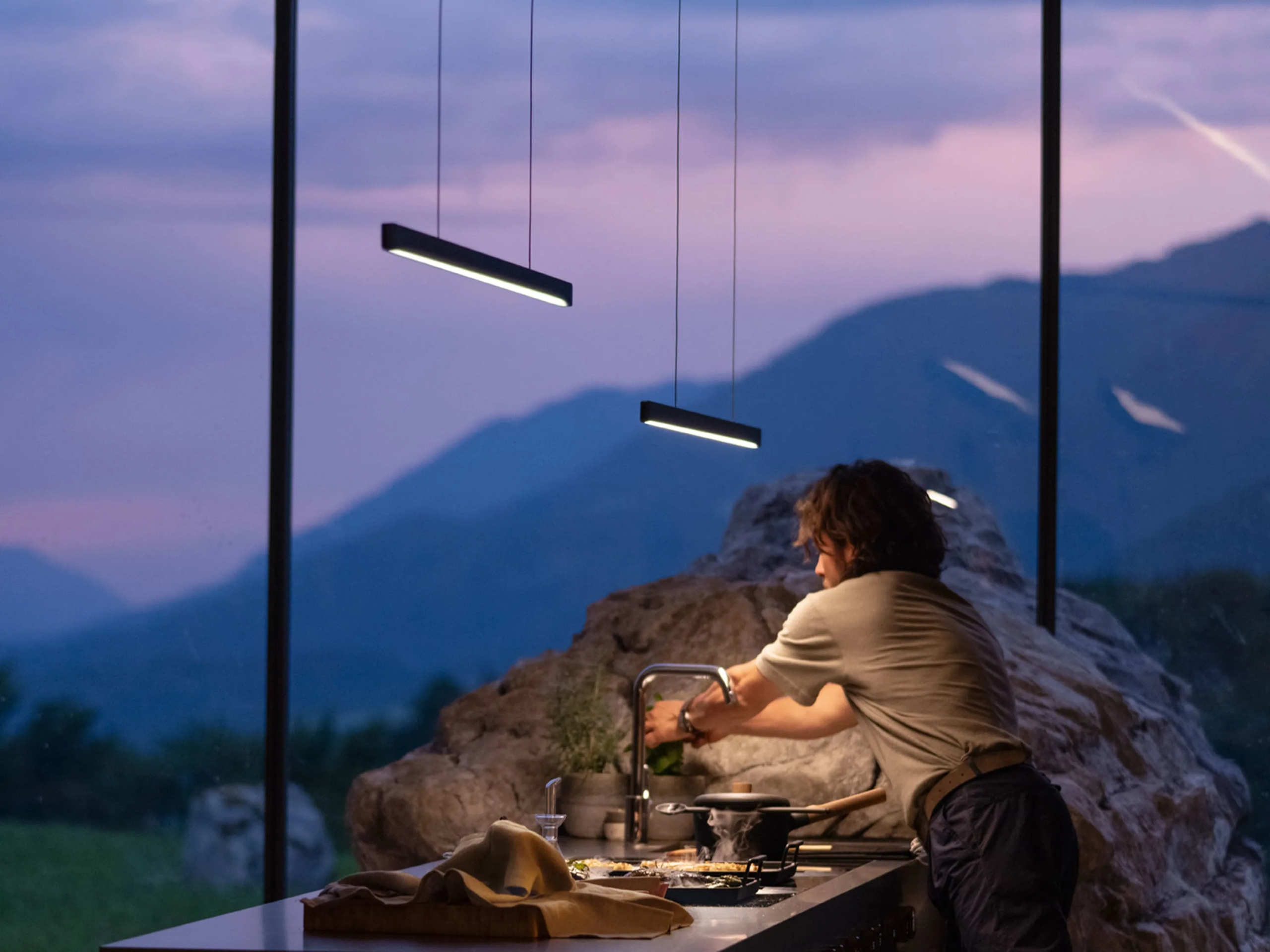 d0vfsrnidncbmscj7odz BORA STARS Horizon viseća lampa iznad kuhinjskog ostrva, stvara toplu atmosferu uz pogled na planine i prirodno kamenje u enterijeru.