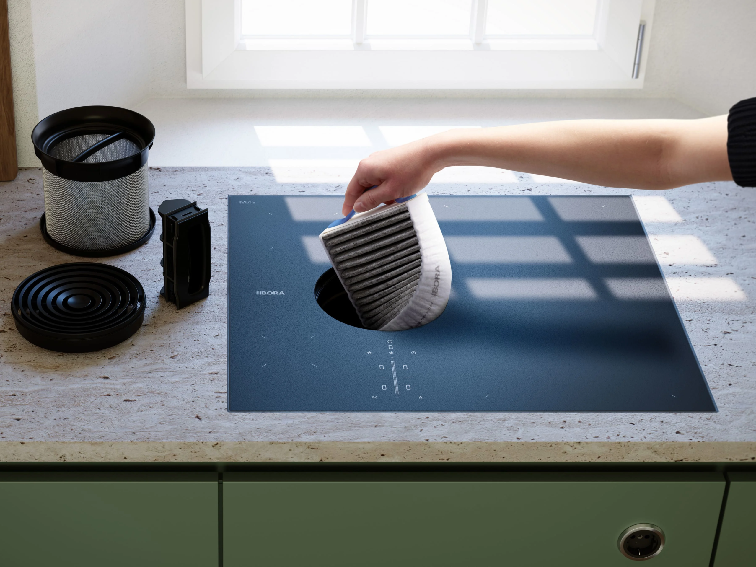 fwsjcyyjokmnqzfareou Zamena filtera na BORA S Pure ploči – ruka ubacuje filter u centralni otvor sistema za aspiraciju pare.