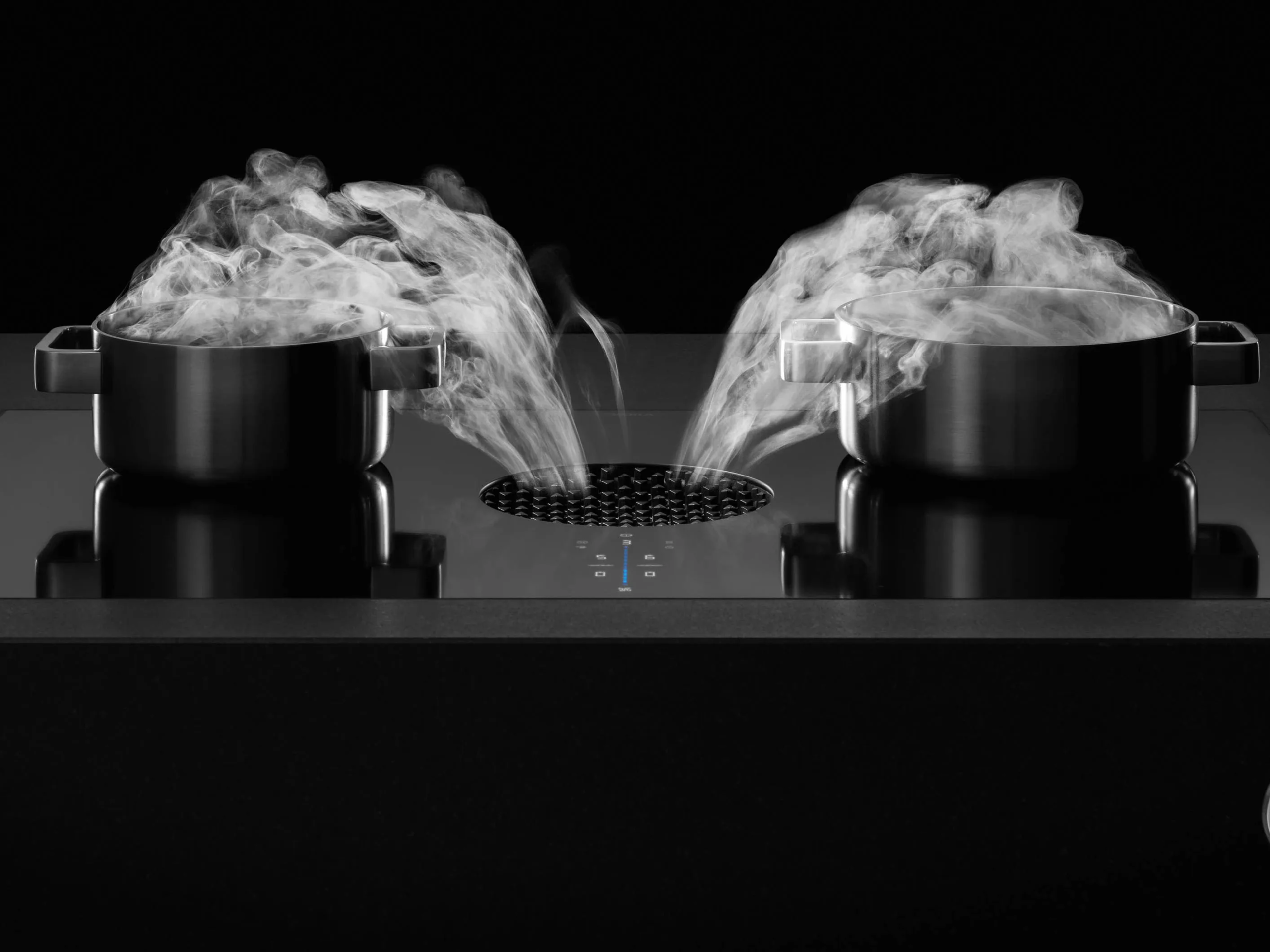 i9oxvq5ofou1r2iwywgy BORA X Pure ploča sa dva lonca u crnom okruženju, para se nežno usisava kroz središnji otvor sistema za aspiraciju.