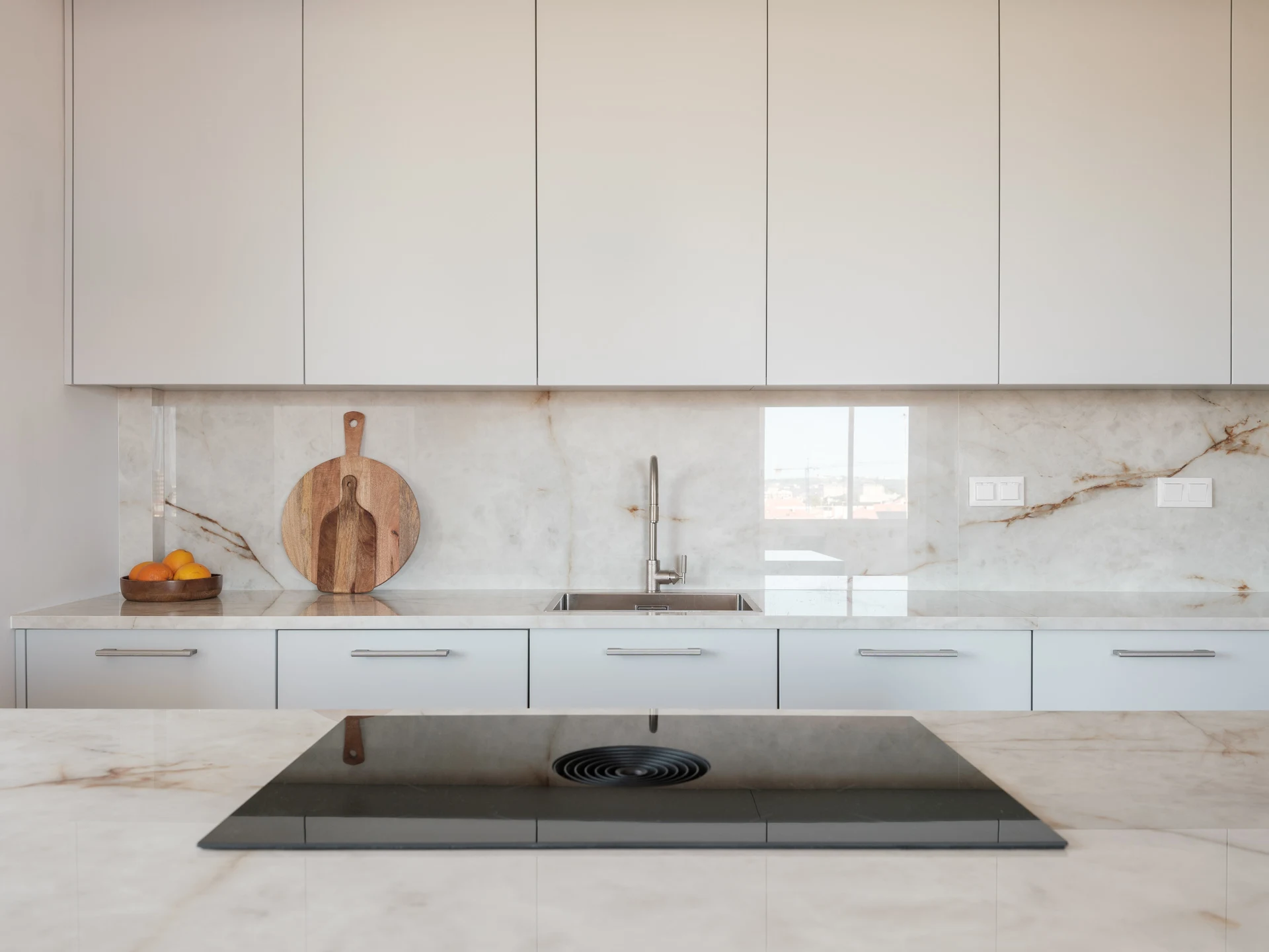 vv8cmo2mbjleny9ehuuo BORA Pure ploča sa centralnim aspiratorom ugrađena u mermernu radnu površinu u modernoj, svetloj kuhinji.